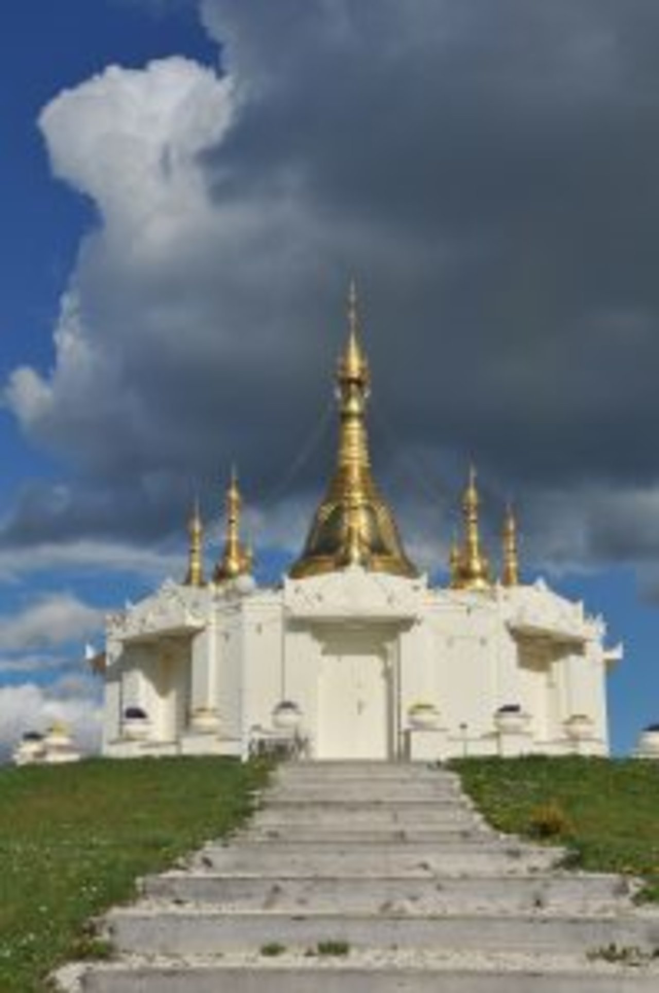 Die Stufen hinauf zur Padoge, die in strahlendem Weiß erleuchtet ist und ein goldenes Dach trägt.