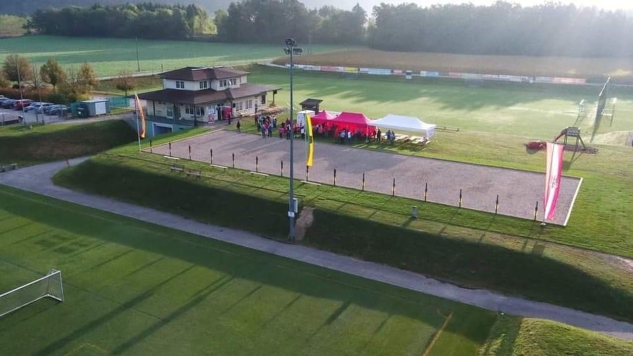 Eine Luftaufnahme des Sportzentrums zeigt das Fußballfeld, die Boccia-Bahn und das Vereinshaus und bietet einen klaren Überblick über die Anordnung der Sporteinrichtungen auf dem Gelände.